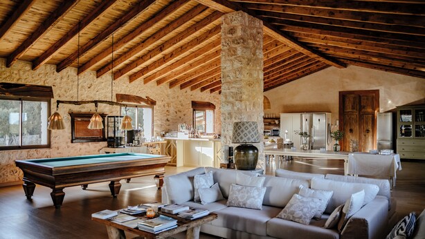 A spacious living area with a pool table, a sofa, and a kitchen in the background. - Finca Gomera, Luxury Country House (Llucmajor)
