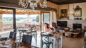 A spacious living area with a large TV, a fireplace, and a dining area with chairs and tables. - Finca Gomera, Luxury Country House (Llucmajor)