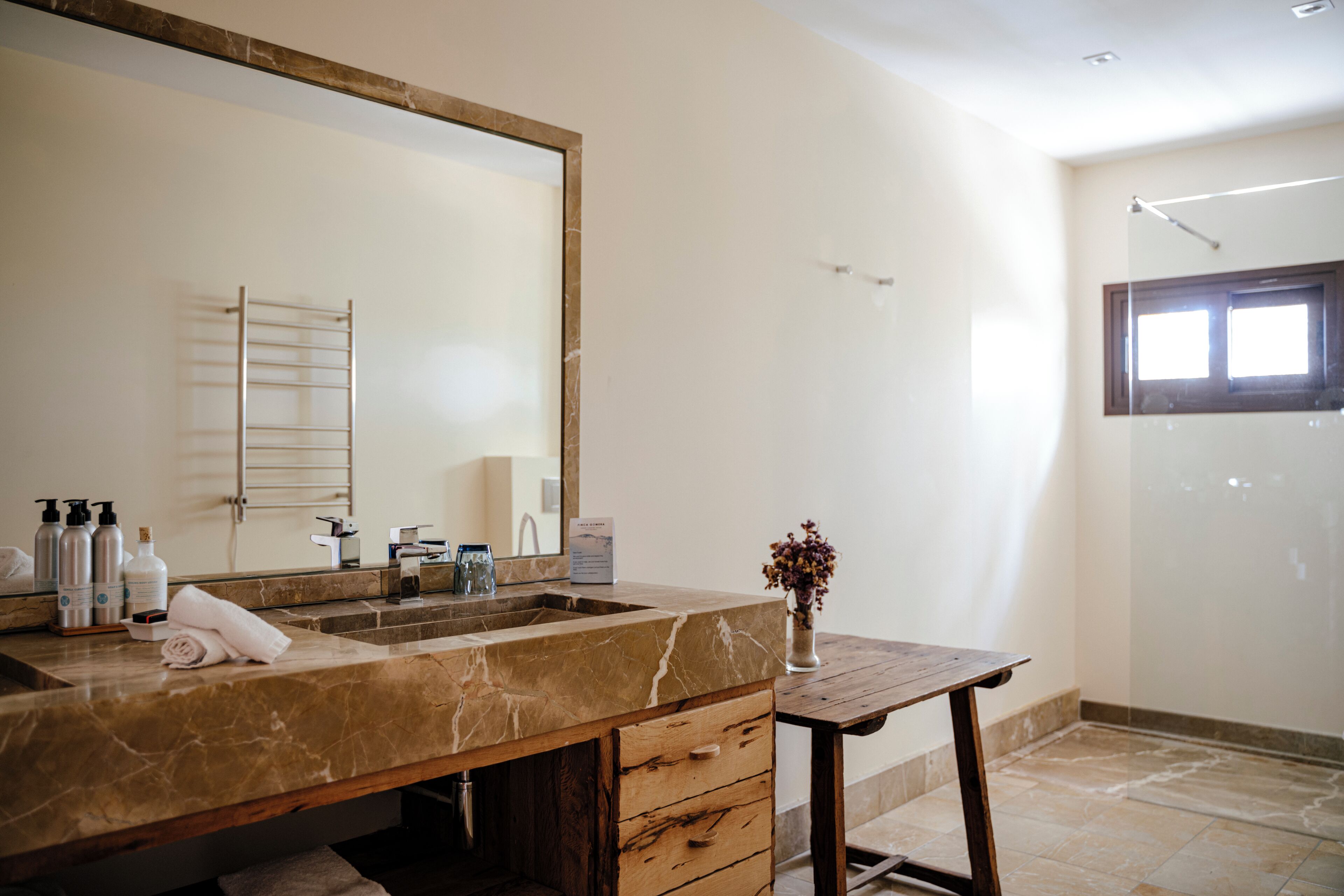 A bathroom with a marble sink, wooden vanity, and a large mirror.