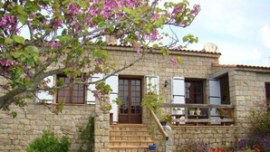 A stone house with a wooden staircase leading to a balcony. - Charming house near the sea South Corsica (Sollacaro)