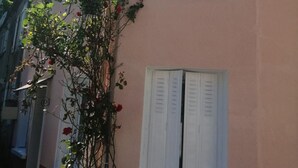 Ein Gebäude mit einer rosafarbenen Fassade, weißen Fensterläden und einem Fenster mit weißem Rahmen.