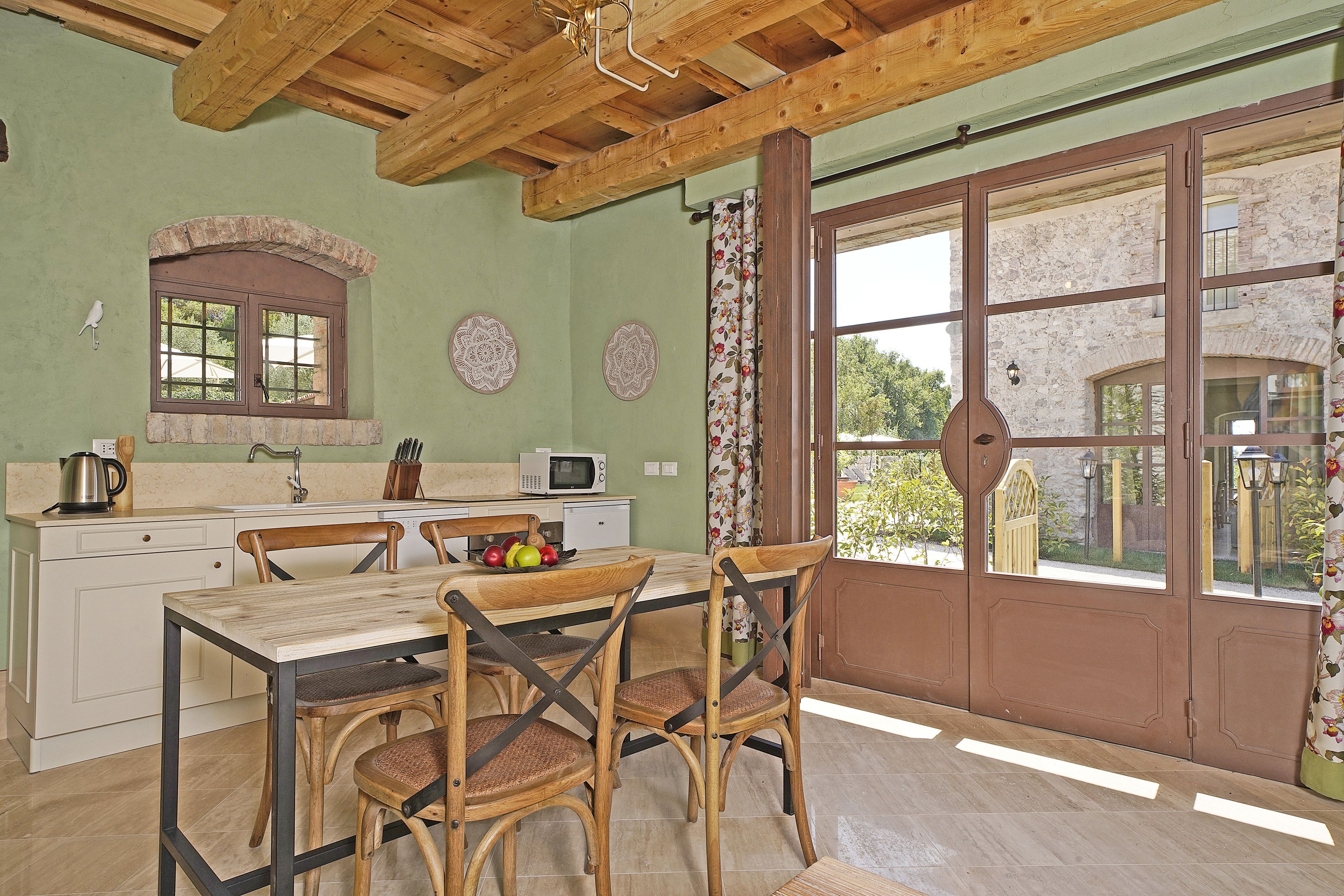 Une cuisine avec une table et des chaises en bois, une fenêtre avec des rideaux et une vue sur l’extérieur.