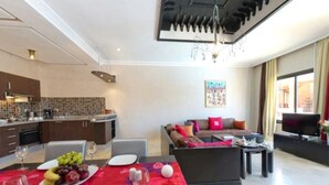 Un espai modern d'estar amb zona de menjador, cuina i saló amb televisió.