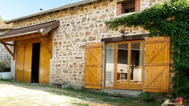Un bâtiment rustique en pierre, doté de volets en bois et d’un petit balcon.