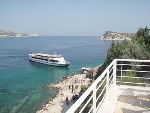 Un ferry atracado en una zona costera con aguas azul turquesa y un litoral rocoso.