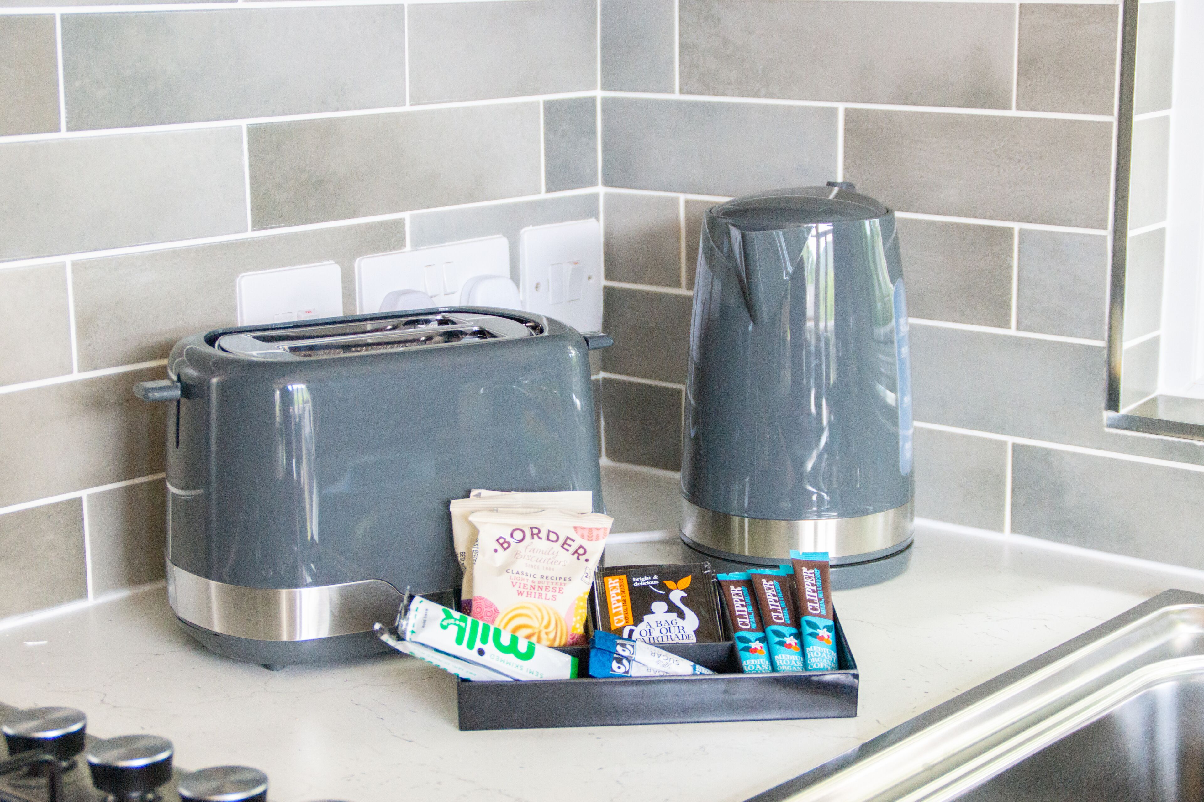 A kitchen with a toaster, a coffee maker, and a tray of snacks.