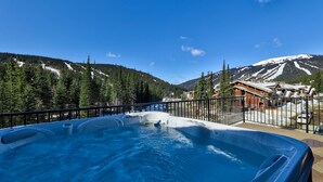 Un jacuzzi con vistas a un paisaje montañoso y un edificio al fondo.