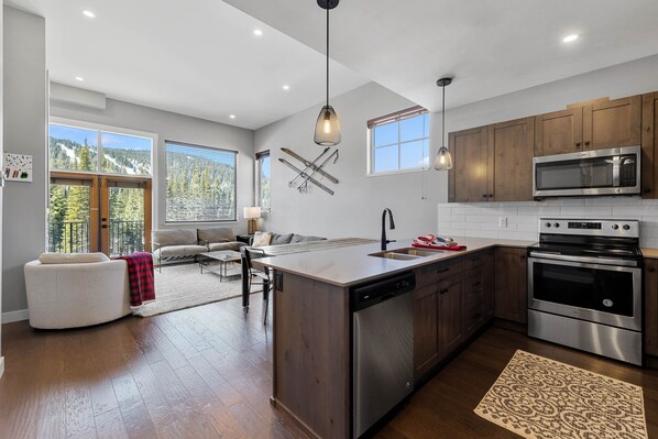 A modern kitchen with a large island, stainless steel appliances, and wooden cabinets.