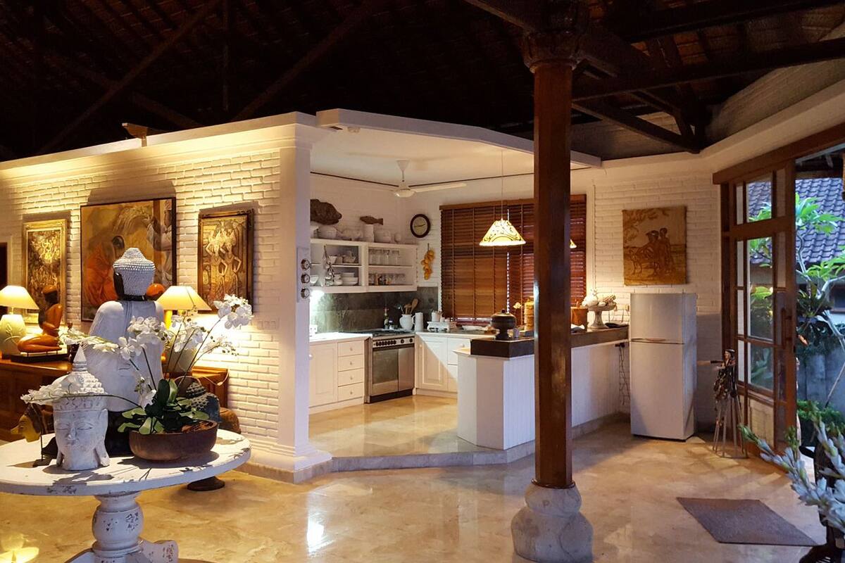 A spacious kitchen with white cabinetry, a central island, and a dining area with a table and chairs.