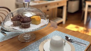 A dining table with a clear glass dome displaying muffins, a white cup and saucer, and a polka-dotted tablecloth. - Le camere di Bsuites (Parma)