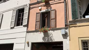 Un edificio con diverse finestre, alcune dotate di persiane, un basculante per garage e un cartello che segnala un'area di parcheggio.