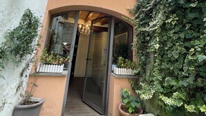 A two-story building with a glass door entrance, potted plants, and a small garden area. - Le camere di Bsuites (Parma)