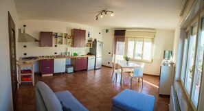Eine kleine Küche mit Essbereich, einer Couch und einem Fenster mit Jalousien.