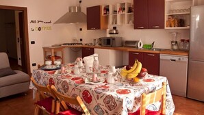 A cozy kitchen with a dining table set for four, equipped with a microwave, toaster, and various kitchen appliances. - B&B Marameo (Udine)