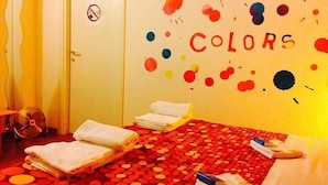 A room with a bed covered in a red and yellow polka dot blanket, a white door, and a wall with the word "COLORS" painted in a colorful splatter pattern. - B&B Marameo (Udine)