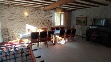 Une pièce rustique avec un mur en pierre, des meubles en bois, une table de baby-foot et un téléviseur.