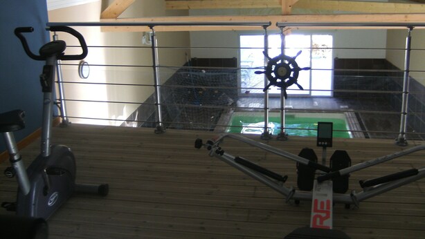 Una palestra con attrezzature per esercizi, un soffitto con travi in legno e una finestra.