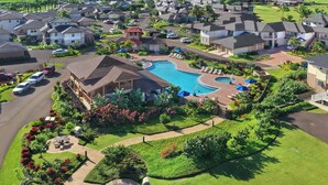 A residential area with houses, a swimming pool, and a golf course in the background. - Pili Mai 3L Newly Upgraded 3 Bedroom Suite in Poipu - AC, Pool & Fitness Center (Koloa)