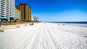 A beach with a sandy path and tall buildings in the background. - Beautiful End Unit Oceanfront in the heart of Myrtle Beach indoor and outdoor pools 203 (Myrtle Beach)