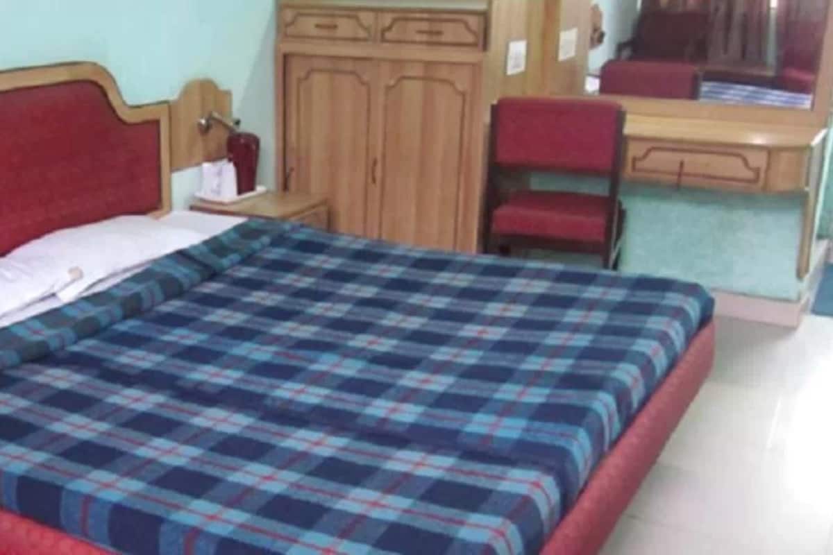 A bedroom with a bed, a nightstand, a desk, and a wardrobe.