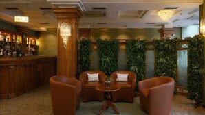 Una zona de bar con muebles de madera y un candelabro, rodeada de exuberante follaje.
