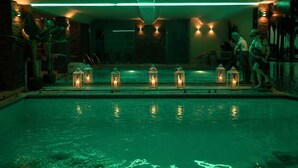 A pool area with a series of lanterns along the edge, a stone wall, and a person standing by the pool.