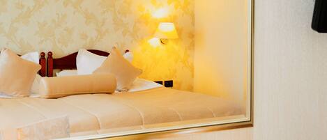 A hotel room with a bed, pillows, a nightstand, a lamp, a coffee maker, and a telephone.