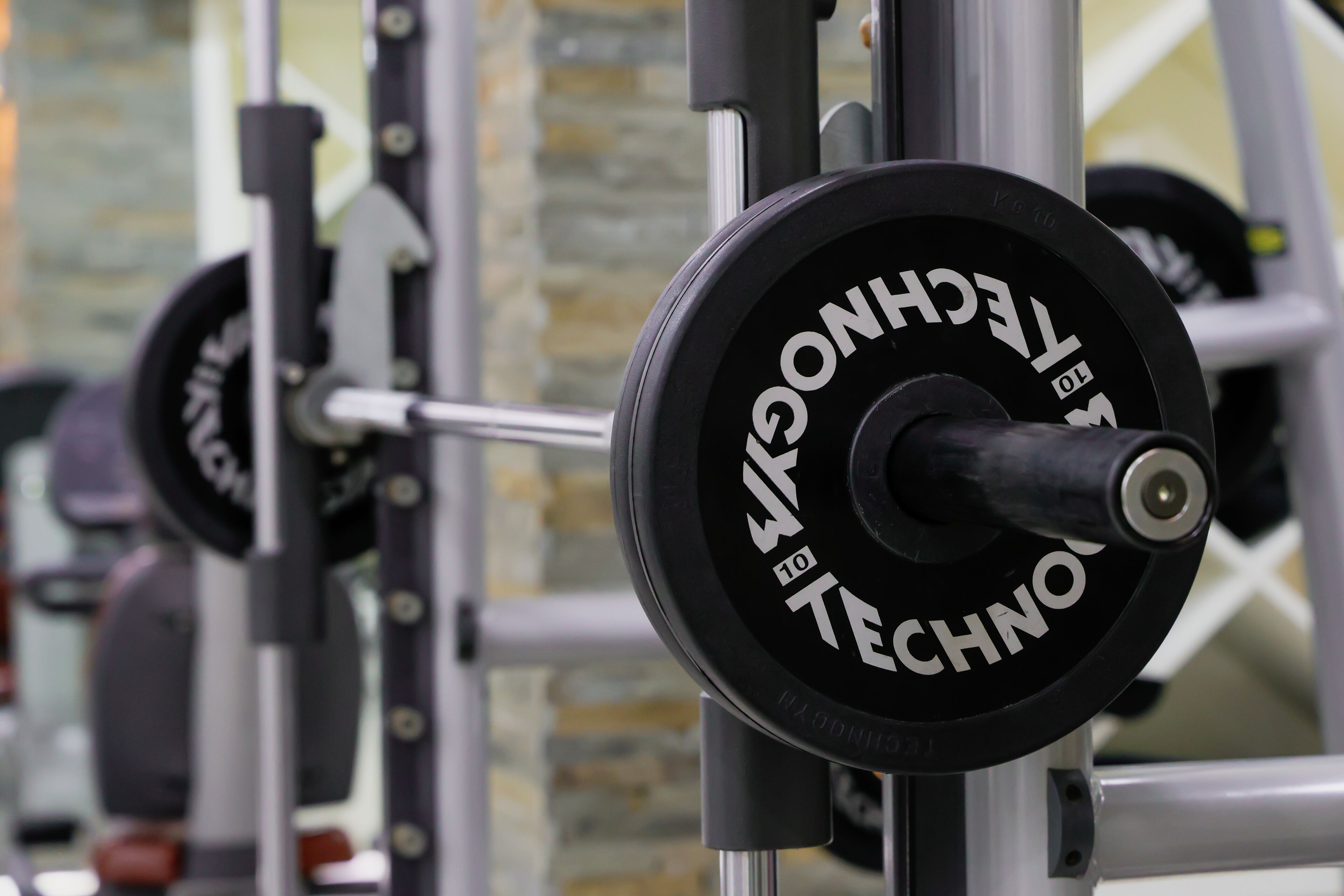 A weightlifting machine with a barbell and weight plates, part of a gym equipment setup.