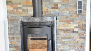 A wood-burning stove with a black exterior, set against a mosaic tile wall. - Holiday house Karin Tassius - Holiday Karin Tassius (Vöhl)