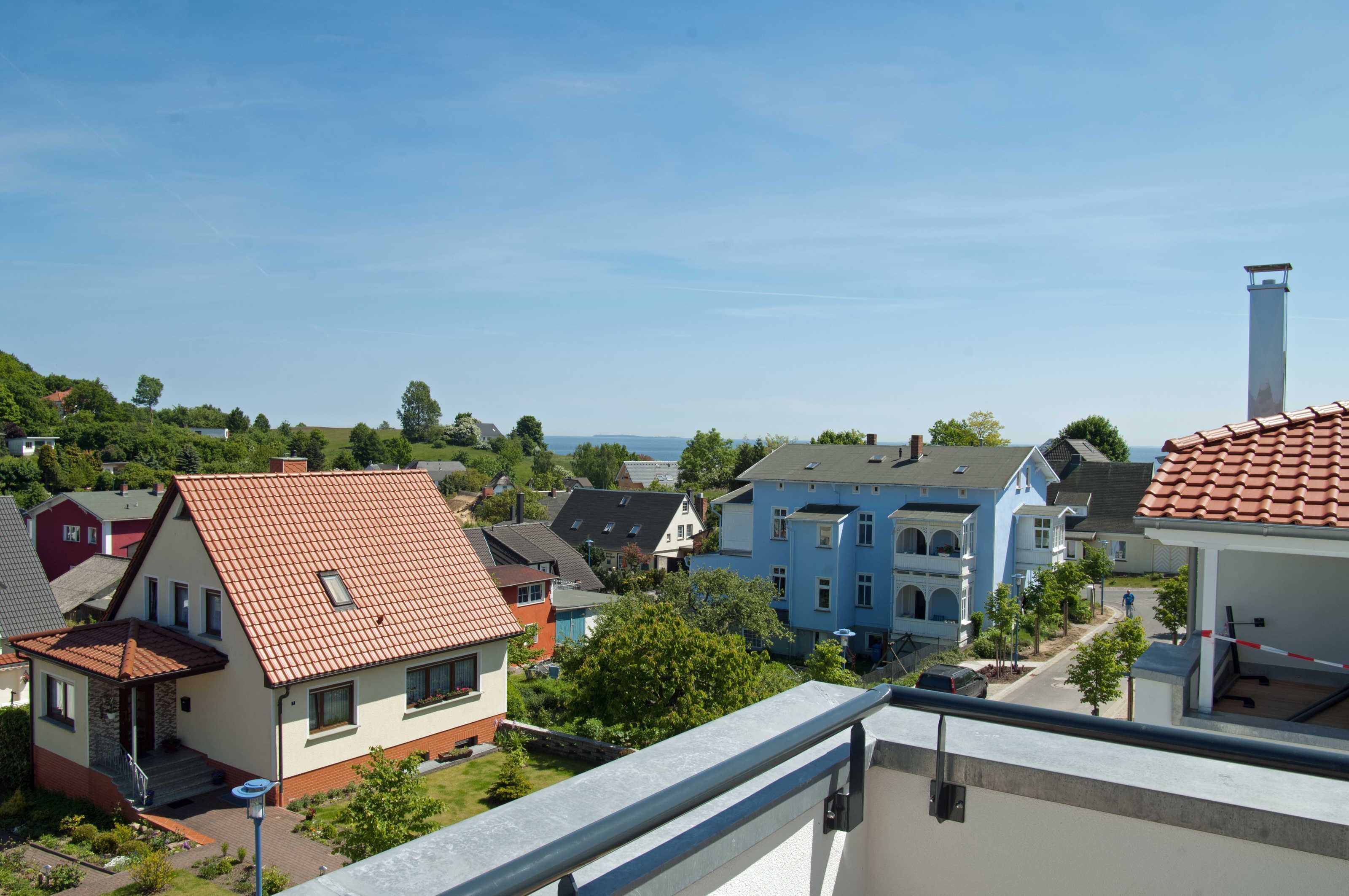 Zona residencial con casas, cielo despejado y una vista distante del mar.