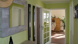 A hallway with a mirror, a door, and a view into a room with a cabinet and a plant. - Penthouse sea view - Apartment sea view in the penthouse (Göhren)