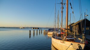 A calm harbor with boats docked, a clear sky, and a distant shoreline. - Penthouse sea view - Apartment sea view in the penthouse (Göhren)