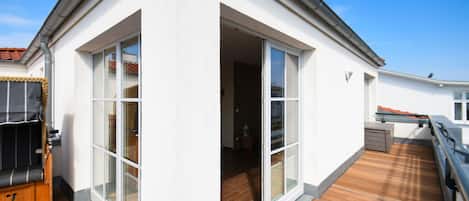 Una casa moderna con terraza de madera, grandes puertas corredizas de vidrio y un pequeño espacio de estar al aire libre.