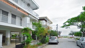 A residential street with two-story houses, a gated entrance, and a parked car. - Themis 40 steps from beach - Dionisiou Halkidiki (Paralia Dionisiou)