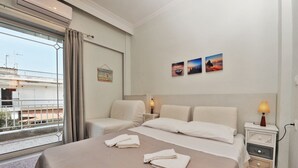 A hotel room with a bed, two bedside tables, a window with curtains, and artwork on the wall. - Themis 40 steps from beach - Dionisiou Halkidiki (Paralia Dionisiou)