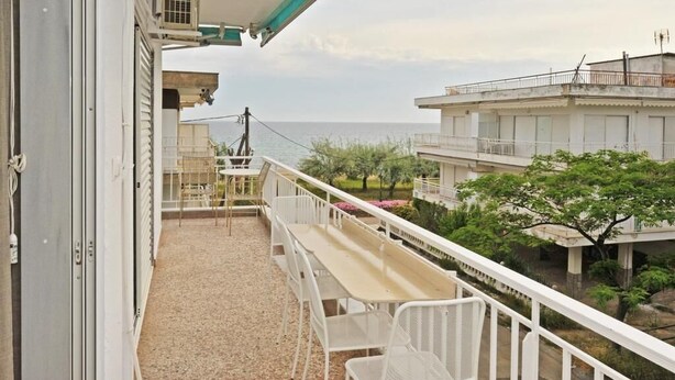 A balcony with a table and chairs, overlooking a residential area and the sea. - Themis 40 steps from beach - Dionisiou Halkidiki (Paralia Dionisiou)