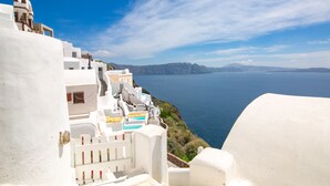 Un edificio costero de paredes blancas con una escalera que lleva a un balcón con vistas al mar.