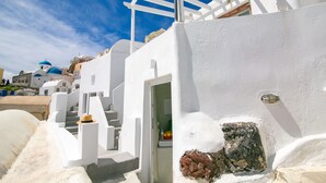 Un edificio de paredes blancas con una puerta que da a una habitación, una escalera blanca y una cúpula azul al fondo.