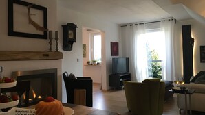 Een woonkamer met een open haard, een televisie en een eethoek met een taart.