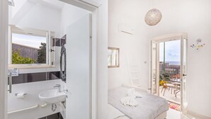 A modern bathroom with a sink, mirror, and towel rack. The room has a balcony with a view of the city. - Apartment Entre Les Jardins (Dubrovnik)