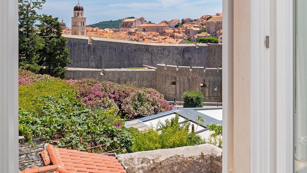 A balcony with a view of a historic cityscape, including a prominent tower and fortified walls. - Apartment Entre Les Jardins (Dubrovnik)