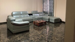 Una sala de estar con un sofá modular, una mesa de centro de madera y piso de mármol.