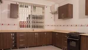 Una cocina con gabinetes de madera, estufa y ventana con mosquitero de metal.
