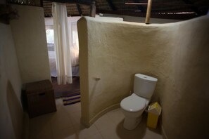 Un baño pequeño y compacto con un inodoro, una caja de madera y una cortina.