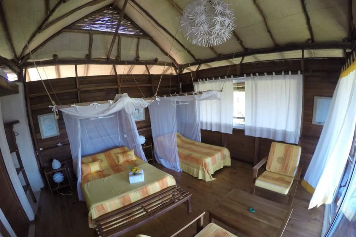 A rustic wooden cabin with two beds, a bench, and a table.