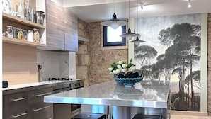 Una cocina moderna con una isla grande, taburetes de bar y una pared decorativa de piedra.
