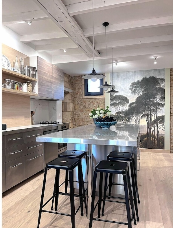Una cocina moderna con una isla grande, taburetes de bar y una pared decorativa de piedra.