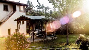 A house with a covered patio, a garden with pink flowers, and a pergola. - Lovely apartment for 6 people with pool, WIFI, TV and pets allowed, close to San Gimignano (Varna)