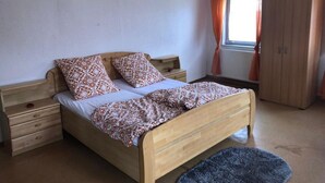 Une chambre à coucher avec un lit en bois, deux tables de chevet, une armoire et un luminaire suspendu.