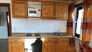 Une cuisine avec des meubles de rangement en bois, un four à micro-ondes, une cuisinière et un lave-vaisselle.